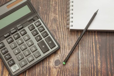 Not defteri ve kalem, iş kavramı ve tasarruf finansmanı ile ahşap arka plan modern hesap makinesi