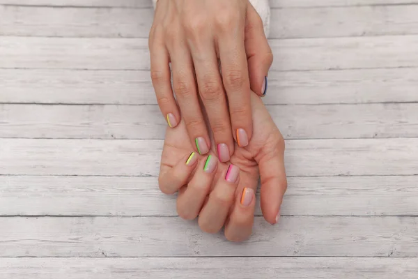 Manicure moderna multicolore, design delle unghie. Modo estivo, su sfondo di legno. Vista dall'alto — Foto Stock