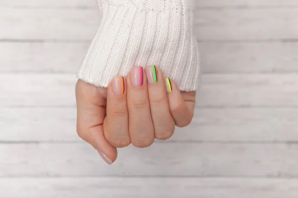 Close-up. Belas mãos de mulher tratada com unhas coloridas no fundo de madeira. Manicure, conceito de salão de beleza pedicure. Lugar vazio para texto ou logotipo . — Fotografia de Stock