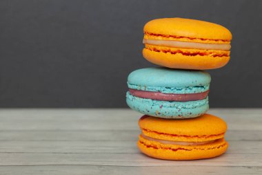 Koyu bir arka plan üzerinde turuncu ve mavi macaroons, tatil için bir tedavi olarak Fransız çerezleri