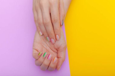 Şık trendy kadın manikür. Mor ve sarı arka plan üzerinde güzel genç kadının elleri. Üstte görüntü
