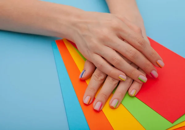 Modern stylish manicure rainbow or summer mood, on a blue table with color envelopes. Close-up