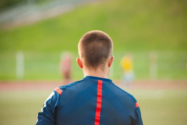 Assistente arbitro di calcio in piedi con la schiena sullo sfondo di un campo di calcio con i giocatori — Foto Stock