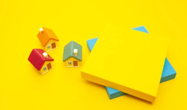 Oyuncak evler ve kağıt çıkartmalar sarı arka planda.