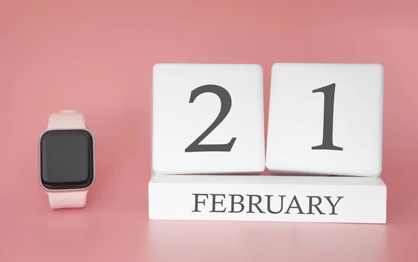 Modern Watch with cube calendar and date 21 february on pink background. Concept winter time vacation.