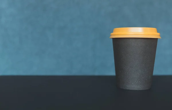 Paper cup of coffee on a green blurred background