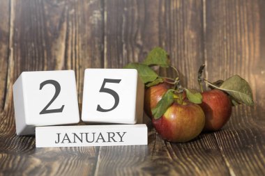 25 Ocak. Ayın 25 'i. Ahşap arka planda kırmızı elmalarla takvim küpü, iş konsepti ve önemli bir olay. Kış mevsimi.