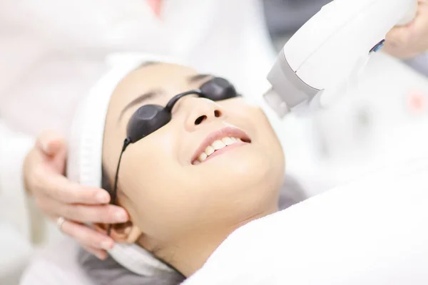 Laser Machine.Young woman receiving laser treatment.Skin Care.Young Woman Receiving Facial Beauty Treatment, Removing Pigmentation At Cosmetic Clinic. IPL. Photo Facial Therapy.Anti-aging Procedures.