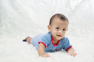 Şirin bebek çocuk stüdyoda ateş ediyor. Bebek ve aile moda görüntüsü. Bebek güzel bir yumuşak beyaz halı üzerinde uzan. görüntü arka plan, duvar kağıdı, kopya alanı, nesneler, moda ve makale için