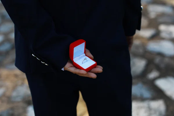 romantic man making a marriage proposal. picture of man with gift box in suit. picture of couple with wedding ring and gift box. close up of man with gift box and engagement ring over holidays .