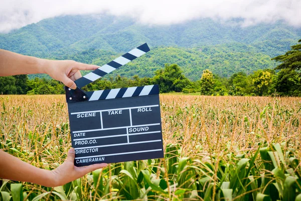 Man hands holding movie clapper isolated on nature background. Shown slate board. use the colors white and black.Realistic movie clapperboard. Clapper board isolated.Film director concept.