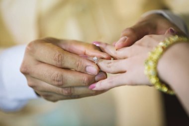 Evlilik yüzükleri. Alyansı ona taktı. Damat, yüzüğü geline tak. Tayland düğün töreni ve Tayland düğün süsü. Damat, yüzüğü gelinin parmağına tak..