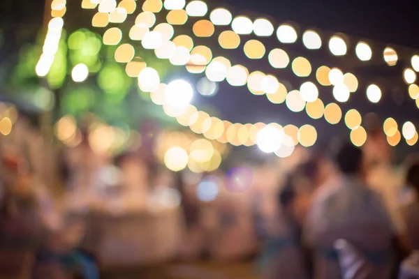 Vintage tone blur image of food stall at night festival with bokeh for background usage. Festival Event Party with People Blurred Background. Blur people having sunset beach party in summer vacation