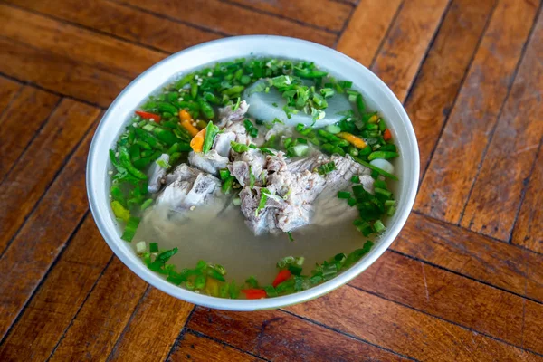 Hot and Spicy Soup with Pork Ribs. Spicy Pork with Pork bone Soup on the Wood Table. Leng soup in Thai word. Hot and spicy pork spare rib soup with tamarind and Thai herbs in bowl, Tom yum.