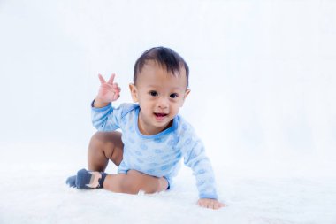 gülümseme bebek çocuk stüdyoda çekim. bebek ve aile moda görüntü. Güzel bebek yumuşak beyaz bir halıüzerinde oturur. arka plan, duvar kağıdı, kopyalama alanı, nesneler, moda ve makale için görüntü