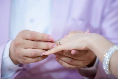 Evlilik yüzükleri. Alyansı ona taktı. Damat, yüzüğü geline tak. Tayland düğün töreni ve Tayland düğün süsü. Damat, yüzüğü gelinin parmağına tak..