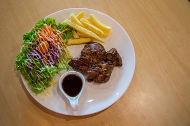 Izgara domuz biftek ve sebze . Masada patates kızartması ve salata ile ızgara domuz eti tabağı. sulu ızgara domuz pirzolası (boyun kesim) yeşillik ile
