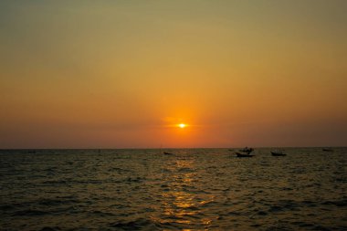 Deniz yüzeyinin altında büyük sarı güneş ile parlak gün batımı. denizde gündoğumu. Denizin üzerinde güzel bir gün batımı. Sahilde tropikal günbatımı.