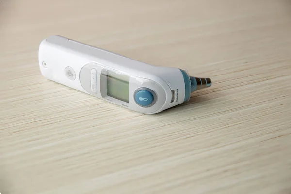 木製のテーブルの上に隔離された医学の耳の温度計 赤ちゃんのためのデジタル温度計 — ストック写真