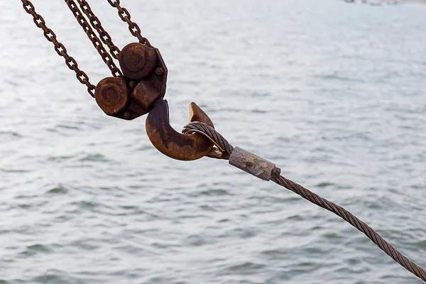Swivel joint and connection with a steel cable when installing the structures outdoor. Rusty Sling With Hook . Hook construction crane with slings near sea.