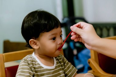Anne bebeği kaşıkla besliyor. Anne evde onun sevimli çocuğa sağlıklı yiyecek veren. kadın bebek yemek ve oturma veren
