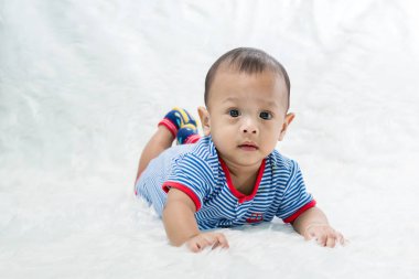gülümseme bebek çocuk stüdyoda çekim. bebek ve aile moda görüntü. Güzel bebek yumuşak beyaz halı üzerinde yalan. 