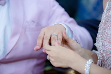 Evlilik yüzükleri. Nikah yüzüğünü He 'ye taktı. Gelin, Yüzüğü Damada Giydir. Thai düğün töreni ve Tayland düğün süsü. Gelin, damadın parmağına yüzüğü tak..