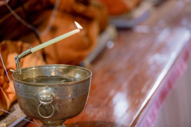 Buda keşişi şamdanı kutsal su kabının üstünde tutuyor. Din töreni. Budist kutsal suyu. Kopyalama alanı için resim.