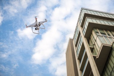 Yüksek çözünürlüklü dijital kamera ile Drone şehir üzerinde uçan . Yükseltilmiş iniş takımları ve bir kamera ile uçan bir multi-copter bir havadan görünümü . Dijital kameralı İhA drone quadcopter.