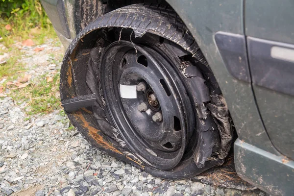 Destroyed blown out tire with exploded, shredded and damaged tire on a modern automobile. damaged truck rubber after tire explosion at high speed. Damaged flat tires: old car.