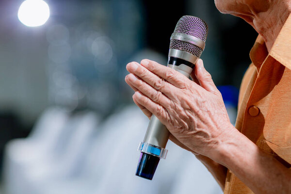 Мужчина держит микрофон двумя руками. Две руки, держащие микрофон в конференц-зале, дают друг другу возможность обменяться идеями.
