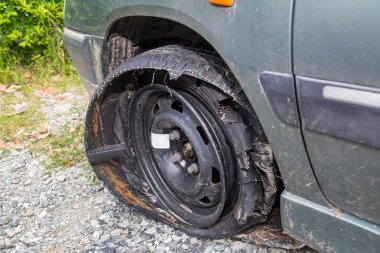 Destroyed blown out tire with exploded, shredded and damaged tire on a modern automobile. damaged truck rubber after tire explosion at high speed. Damaged flat tires: old car. clipart