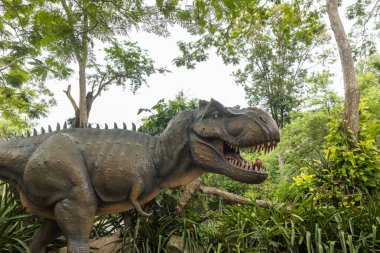 Tehlikeli tarih öncesi dinozorlar Tyrannosaurus Rex, vahşi yaşamda T-rex. Ormandaki Tyrannosaurus Rex (T-Rex) başkanı. Orman parkında dinozor heykeli , doğada dinozor heykeli görüntü arka plan