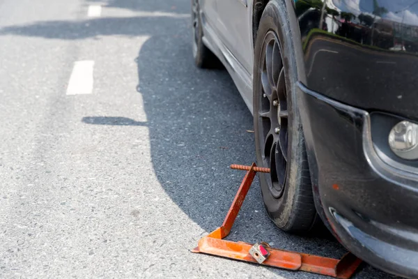 Locked wheel of a car parked in an improper place. Car wheels locked, traffic violation. Black car get locked up by the police. Illegal parking in the restricted area resulted in wheel