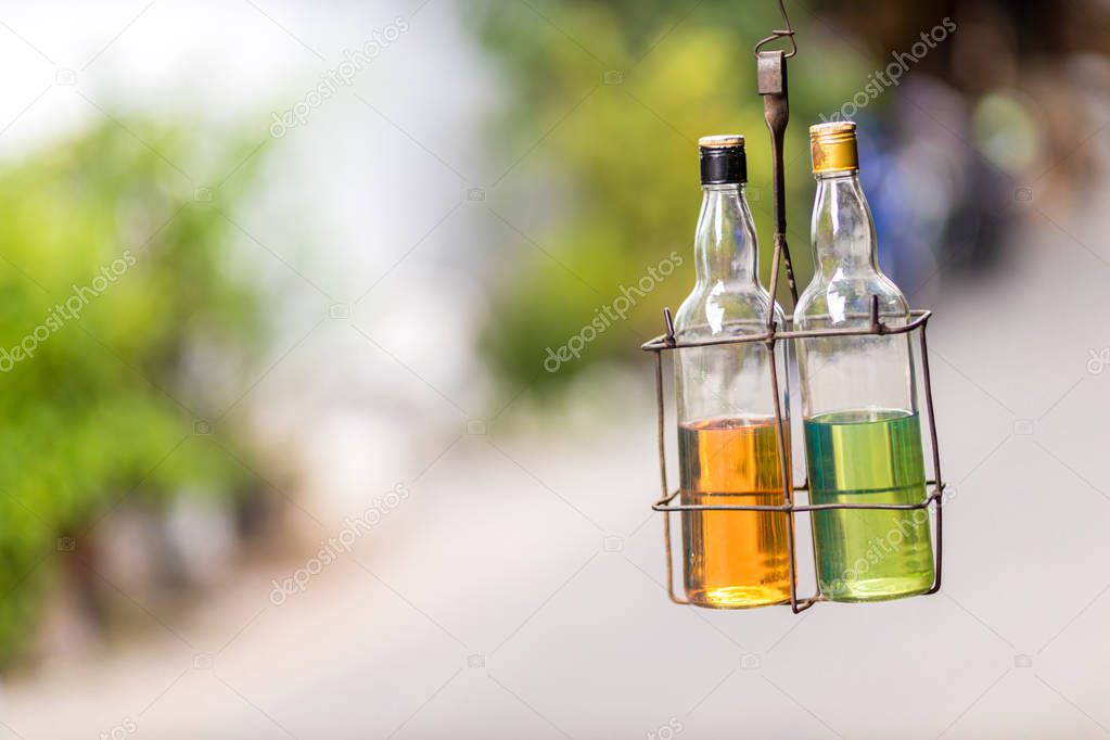 Petrol /gasoline for sale on the street in reused glass bottles. Glass bottles with gasoline hang near the store. 