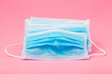Pembe arka planda koruyucu yüz maskesi. Ağız ve burnu örtmek için tipik 3 katlı cerrahi maske. Bakterilerin prosedür maskesi. Koruma konsepti. Plastik kulaklıklı cerrahi maske. covid 19