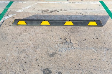 Siyah-sarı lastik tekerlek durduruculu boş otopark. Park yeri park yeri yapmak için ayrılmıştır. Her araba beyaz bir çizgiyle, çimento tekerlek durduruculu..