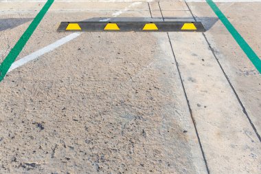 Siyah-sarı lastik tekerlek durduruculu boş otopark. Park yeri park yeri yapmak için ayrılmıştır. Her araba beyaz bir çizgiyle, çimento tekerlek durduruculu..