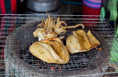 Kömür ocağında ızgara mürekkep balığı. Izgara kalamar çok lezzetlidir. Tayland sokak yemeklerinde bulunur. Sıcak kömürde barbekü ızgarası. Izgarada kömür ızgaralı taze kalamar..