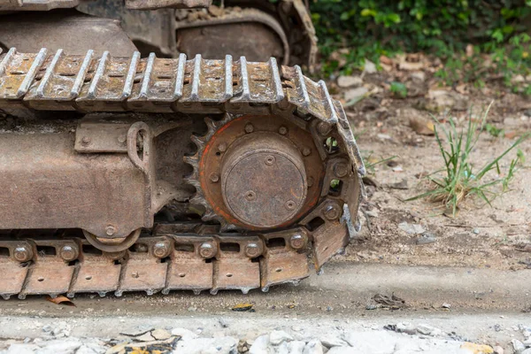 Excavator tracks. Old iron caterpillars of the bulldozer of the tractor on the road. bulldozer caterpillar tracks. Black caterpillar tractor grader with the wheels on the ground.