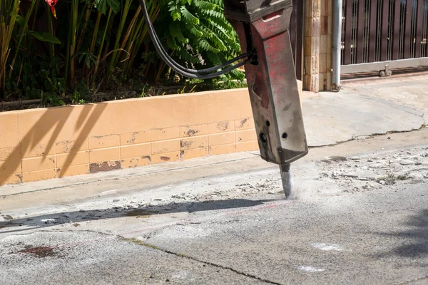 Excavator breaking and drilling the concrete road for repairing. Large pneumatic hammer mounted on the hydraulic arm of a construction equipment.Construction Vehicles repairing road.drilled jackhammer