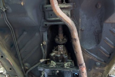 Garajdaki eski arabanın arka tekerlek dingilinin altında tamir kirli. Araç şaftı güç iletimi dingil araba tekerleği