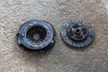 Eski disk debriyaj ve yerde kaplama. Eski paslı debriyaj ve disk garajda duruyor. Araba paslı debriyaj baskı plakası. Debriyaj plakası ve uçuş tekeri var.