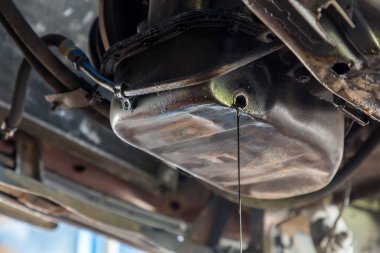 Motordaki eski yağı boşaltım kapsülünden boşalt. Araba motorunun yağını değiştirmek. Motorlu araçtan atık yağ boşaltımı. Kullanılan dizel motor gücünü yağ tavasından bir konteynıra boşaltma 