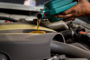 Tamirhanedeki tamirci, tamirhanedeki tamirciye, tamirciye, tamirciye yağ dolduruyor ve motora taze yağ döküyor. Yağ değişimi sırasında arabaya taze yağ dökülüyor.