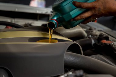 Tamirhanedeki tamirci, tamirhanedeki tamirciye, tamirciye, tamirciye yağ dolduruyor ve motora taze yağ döküyor. Yağ değişimi sırasında arabaya taze yağ dökülüyor.