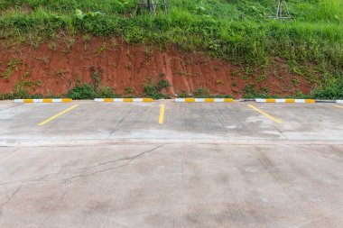 Çiçekleri düşen bir otoparkta boş bir alan. Sol duvarı olan bir park arabası. Parkın dışına park etmiş..