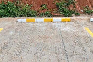 Lastik durdurma betonu, açık hava park alanının sarı ve beyaz boyası, Lastik Tekerlek Durucu / Park alanı. Otomobil yolunda sarı tabela