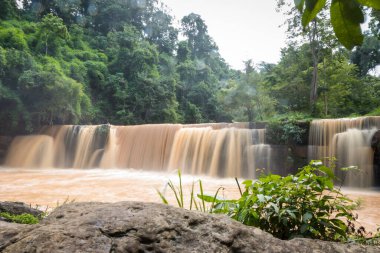 Şelalede ani sel. Yağmur ormanlarındaki ani selden kaynaklanan şelale. Tropikal yağmur ormanlarından gelen kahverengi şelaleden taşan sel..