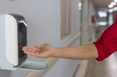 Ellerini otomatik alkol kutusunun altına koy. Enfeksiyon ve konuksever konsept. Hastalık virüsünü mikroplara karşı koru ve kamuya açık alanda temizle.. 